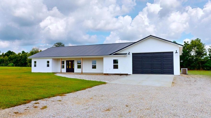 Experience the perfect blend of modern comfort and rustic charm in this brand-new custom farmhouse, offering over 4,000 sq. ft. under roof. Nestled at the end of a private gravel drive, this stunning property welcomes you with young pecan trees and leads to a 4-car garage with a spacious workshop/hobby area. The exterior showcases a rock border, a rock garden at the entry, and stately cedar posts framing the front porch, complemented by poplar wood ceilings. Step inside and you'll find a thoughtfully designed floor plan beginning with a laundry room and half bath. Continue down the hallway to a dedicated office or the first of three guest bedrooms, where the sleek, uniform track lighting creates a seamless aesthetic throughout the home.