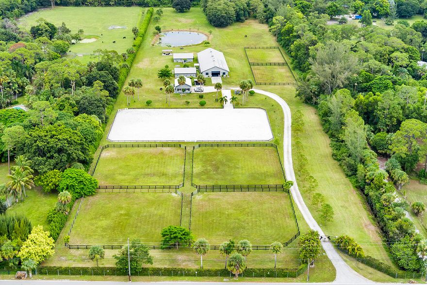 Beautiful 10-acre property with center aisle poured concrete barn- 8 supersized stalls, all with hurricane shutters and screens, 2 wash stalls, full bathroom, tack room, 2 utility/feed rooms, and laundry room. Solar panels for barn and apartments. Oversized 3 car garage. 2 living structures, a 2 bedroom 1 bath with an efficiency and a separate entrance, as well as a large one bedroom one bath house. Newer central A/C units throughout. The 6 paddocks all have new fencing, sand ring with great drainage and improved footing. Pond- beautiful pastures, private- fully fenced with privacy hedge. Solar power entrance gate. There is plenty of room to add more paddocks, a private home, etc. This property is turnkey & only 20-30 minutes from the Wellington Equestrian Center.