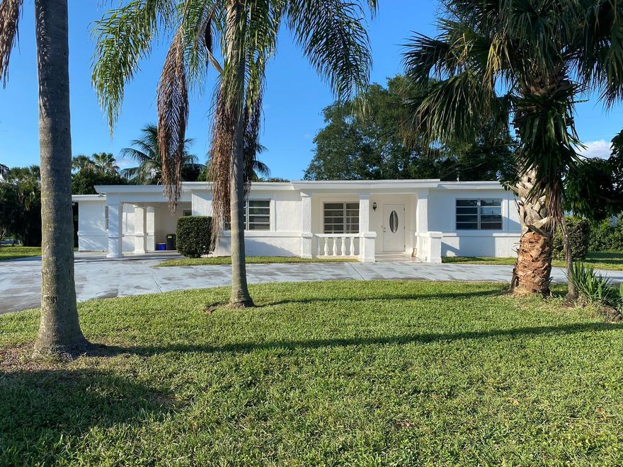 A rare waterfront property set on a premium corner lot, featuring a new boat dock, on one of the most sought-after streets in Lake Clarke Shores. Ideally situated on a quiet canal just one home from the widest section of Lake Clark. Unlike typical waterfront homes, this home's water views are not into neighboring backyards, but instead enjoy a more tranquil, tropical view. Close enough to the wide lake for exciting boating, waterskiing and jet skiing yet set back just enough to enjoy quieter, calmer waters. The property features a new boat dock with composite deck (constructed in 2025) and a seawall spanning the length of the generous corner lot backyard.  From the backyard dock, enjoy direct access to an extensive freshwater boating network connecting Lake Clarke to Lake Osborne and Lake Ida—perfect for exploring miles of scenic waterways. The home offers over 2,200 total square feet with a versatile floor plan, including 4 bedrooms and 3 full bathrooms, plus a living room and family room. Two primary bedroom suites are thoughtfully positioned apart from the additional bedrooms. One suite features a private exterior entrance—ideal for an in-law suite, guest quarters, or potential rental opportunity. A second bedroom also includes its own exterior access, offering additional flexibility. The family room showcases large windows with tranquil canal views and a sliding glass door leading to a concrete patio. The good-sized kitchen overlooks the backyard and water, providing a functional layout with great potential. Additional highlights include a large circular driveway with ample parking and a covered carport that leads into the laundry room and kitchen. Enjoy waterfront living with a private dock, tranquil canal views, and stunning sunsets — ideal for recreation, relaxing and entertaining. Lake Clarke Shores is a highly-regarded, non-HOA community offering its own police department, a boat ramp, tennis and pickleball courts, playground, and conveniently located very close to ocean beaches, downtown West Palm Beach, Palm Beach Island, PBIA airport, I-95, dining, and more. Buyer to verify measurements and information. Sold As-Is, cash offers only. LWDD Canal and right-of-way. Seller is a licensed sales agent.