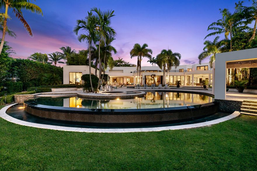 Set on a 1.36 acre lakefront lot, this beautiful contemporary estate was tastefully reconstructed in 2007. Facing west down a peaceful serene lake, this estate offers extreme privacy surrounded by lush tropical palm trees. Features of this residence include 5 bedrooms plus a theater room, office and massage room, infinity edge Pebble Tec Pool, Full house generator, impact windows, and high end summer kitchen. First floor includes the master bedroom, theater, office, massage room and guest bedroom. Second floor includes three guest bedrooms with ensuite bathrooms and a loft.