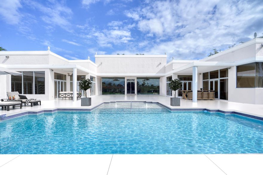 Lakefront tennis estate on 1.25 acres in Boca Raton's prestigious Long Lake Estates, offering 300 feet of water frontage, private tennis court, and expansive indoor-outdoor entertaining designed for South Florida living. This waterfront residence combines scale, privacy, and lifestyle opportunity with a resort-style pool, grand entertaining spaces, and sweeping lake views throughout. Set within one of Boca Raton's most coveted gated enclaves, the home welcomes you with voluminous ceilings, French doors, and marble floors that create a graceful transition through both formal and relaxed living areas. The gourmet kitchen connects seamlessly to the poolside patio, creating a natural setting for entertaining, outdoor dining, and everyday living. Generously scaled bedrooms provide flexibility for guests, multigenerational living, or private office spaces. The primary suite opens to tranquil lake views and features a generous sitting area along with a light-filled bath complete with a spa soaking tub and walk-in rain shower. Throughout the residence, thoughtful proportions and natural light create a sense of quiet elegance and openness. Outside, the grounds unfold across lush, manicured acreage framed by serene water views. Enjoy a resort-style pool, expansive entertaining terraces, and your own private tennis court -- a rare offering that transforms the estate into a true lifestyle compound designed for recreation, relaxation, and hosting on any scale. Located within the prestigious boutique community of Long Lake Estates, residents enjoy privacy while remaining moments from Boca Raton's premier golf clubs, private schools, dining destinations, shopping, and convenient access to Boca Raton Airport and South Florida's beaches. Private previews available by appointment. Photography virtually staged and adjusted.