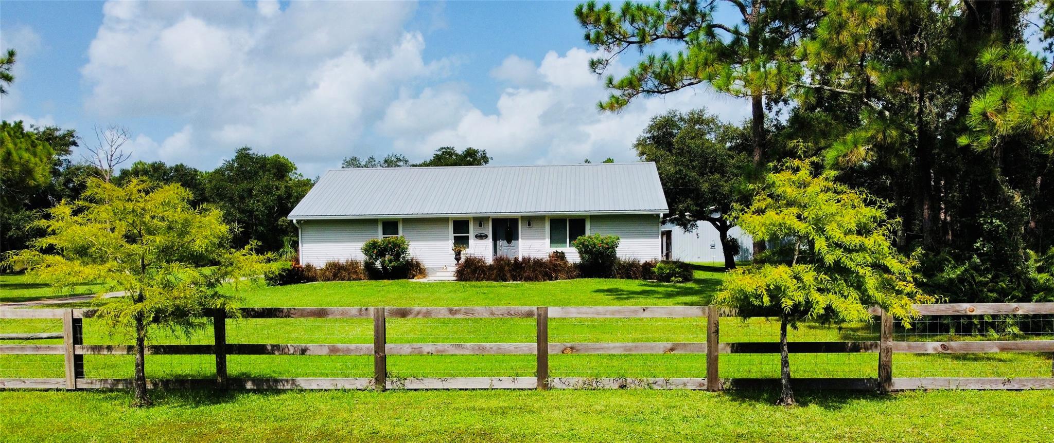 Discover the perfect blend of country living and modern amenities on this 4.73-acre property. The centerpiece of this estate is a beautifully constructed modular home featuring 4 bedrooms and 3.5 bathrooms, including 2 en-suite. With a metal roof, impact windows, propane tankless water heater, whole home generator, and two AC units, this house will keep you cool and safe! Relax on the large screened porch and admire all the wildlife that is home to this property as well. The property also boasts two impressive barns with a 2-bay workshop 30’x30’, 2nd barn is a 72’x40’ structure that includes a wet bar and an air-conditioned man cave/living space, complete with its own separate AC and half bath. This wildlife and sportsman's paradise offers the tranquility of country living and space!