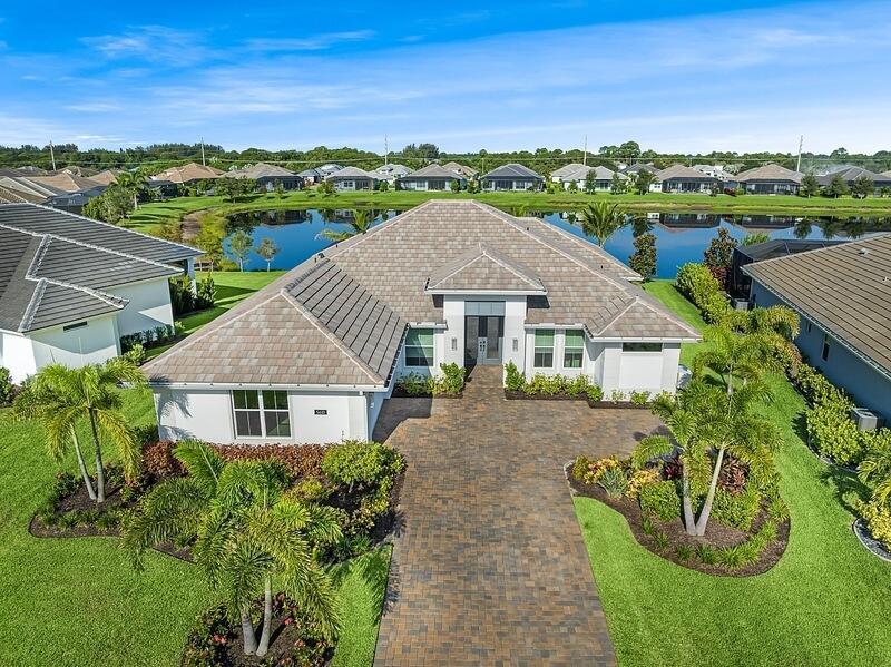 Welcome to this stunning 4 bedroom plus office, 3.5 bath Tavvo Signature home in the exclusive Bent Pine Golf Community, minutes from Vero's sun-drenched beaches and vibrant downtown. Features soaring 14' ceilings, open great room with 10' sliders, elegant tile flooring, and chef's kitchen with premium KitchenAid appliances, gas cooktop, quartz counters, crown molding, and wine cooler. The owner's suite is a true sanctuary, featuring a spa-style bath with soaking tub, oversized shower, and custom closet, plus ensuite guest bedroom. Outdoors, enjoy a heated saltwater pool and spa, lush landscaping and lake views. Impact windows, dual-zone AC, whole-house generator, upgraded lighting, custom closets and motorized blinds, an epoxy-coated garage plus a flex room complete this coastal retreat.