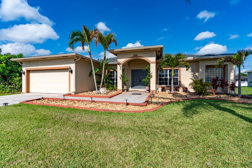Welcome to this beautifully maintained and move-in-ready 4-bedroom, 2-bath CBS home offering 1,910 square feet of comfortable living space in the highly sought-after Becker area of Port St. Lucie. This spacious contemporary home combines thoughtful updates, architectural charm, and exceptional indoor-outdoor living complete with generator connection. Recent improvements provide peace of mind and modern convenience, including a 2021 shingle roof, 2020 air conditioning system, 2021 hot water heater, LG stainless steel kitchen appliances, and  newer washer and dryer. The professionally refreshed landscaping creates outstanding curb appeal. Step inside to discover a bright and airy split-bedroom floor plan filled with natural light. Elegant  tray ceilings in the living room, arched doorways, and multiple sliding glass doors add architectural interest and enhance the open feel of the home. Luxury vinyl flooring flows throughout the main living areas, while all bedrooms feature comfortable carpeting. The spacious kitchen offers both an eat-in breakfast area and easy access to the formal dining room, making it ideal for everyday living and entertaining. Three sets of sliders in the main living areas seamlessly connect the indoors to the expansive outdoor patio, while an additional set of sliders in the primary suite provides direct access to the backyard retreat. The oversized primary suite features a walk-in closet and a luxurious ensuite bath complete with a Roman tub. Outside, enjoy your own private backyard oasis with an extended patio, pergola, and remote-controlled awning—perfect for relaxing or entertaining guests. The pool table is included, making this home truly move-in ready and ready for fun. Situated on a generous 0.23-acre lot with plenty of room for a custom pool, this home also includes storm shutters, public water and sewer, and a 2-car attached garage. Conveniently located near I-95, shopping, dining, and everyday amenities, this exceptional property offers the perfect combination of space, updates, style, and location.