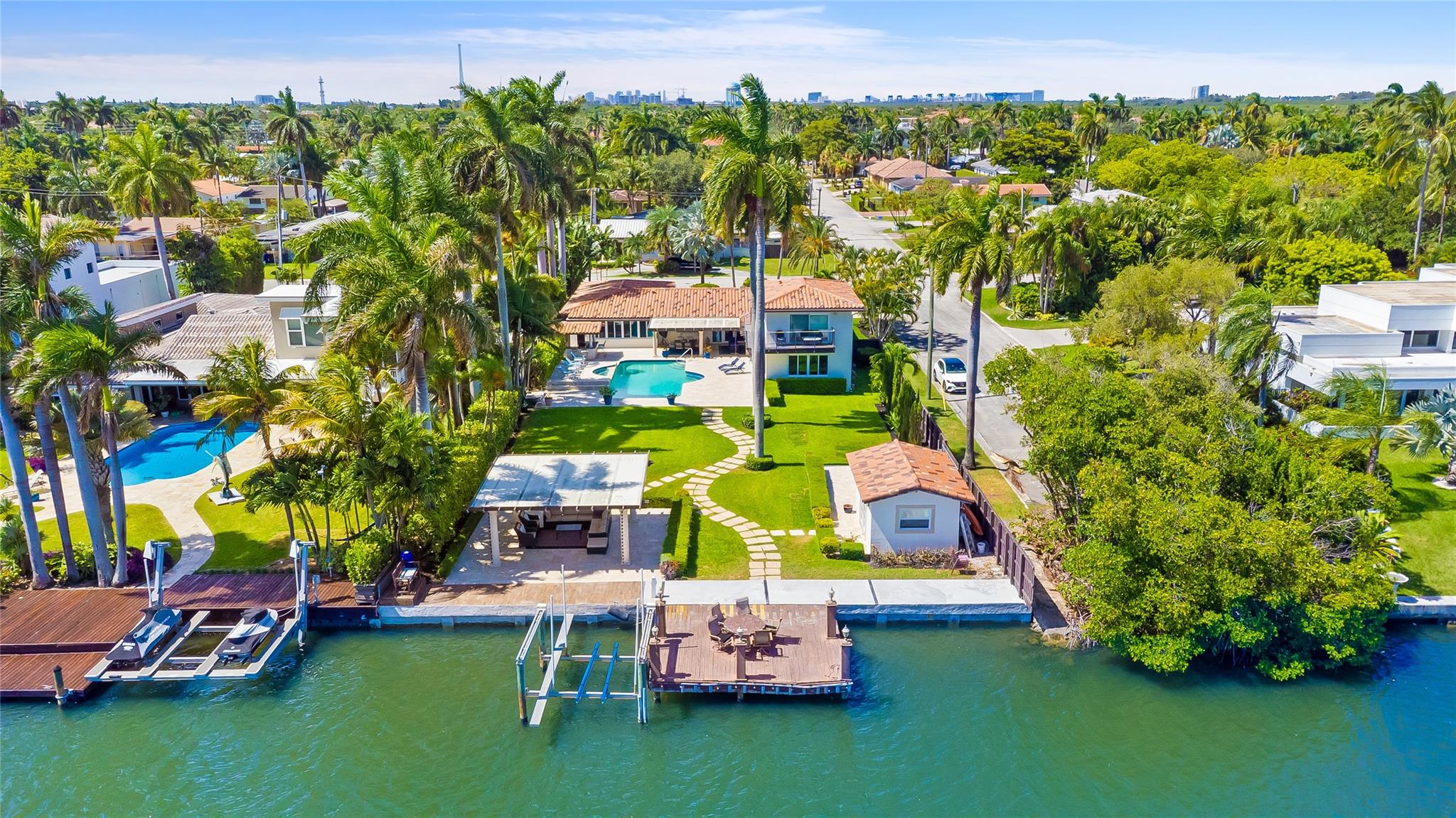 Stunning Lakefront Property! Experience waterfront living at its finest with 80 feet of direct lake frontage and no fixed bridges. This beautiful 5/4 home features a spacious layout, impact windows, and a 2-car garage. Inside, the modern kitchen is equipped with new quartz countertops, new stainless steel appliances, and elegant wood flooring throughout. Step outside to your own private oasis – a large heated saltwater pool with a raised Jacuzzi, and covered pergola on the water. The outdoor space is perfect for entertaining with a fully equipped summer kitchen and a separate casita for guests or additional living space. Surrounded by lush, professional landscaping and offering a large circular driveway, this home blends comfort, luxury, and functionality in a prime waterfront setting.