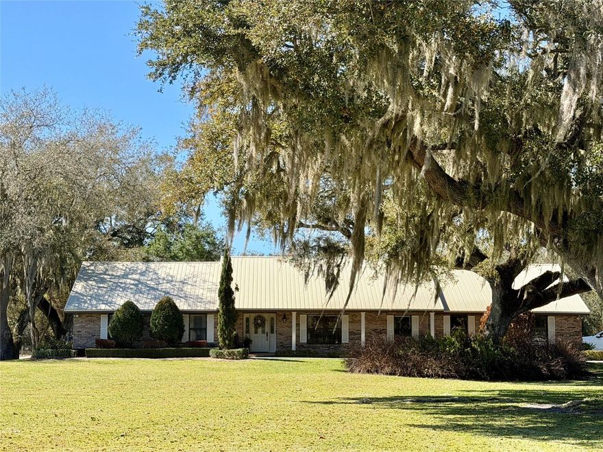Luxury country living meets refined equestrian elegance on 4.99 pristine acres. Set behind majestic oaks draped in Spanish moss, this exceptional Florida homestead blends executive living with refined equestrian amenities in a serene setting. The 4-bedroom, 6-bath executive pool home commands attention with its expansive footprint, classic brick façade, and metal roof, offering timeless appeal. The thoughtfully designed interior provides generous living spaces ideal for both comfort and upscale entertaining, sophisticated living and gathering areas, and spacious bedroom suites. The screened patio area anchors the outdoor living experience. Beyond the home, the property unfolds into a meticulously maintained landscape featuring fenced paddocks and an impressive 8-stall horse barn