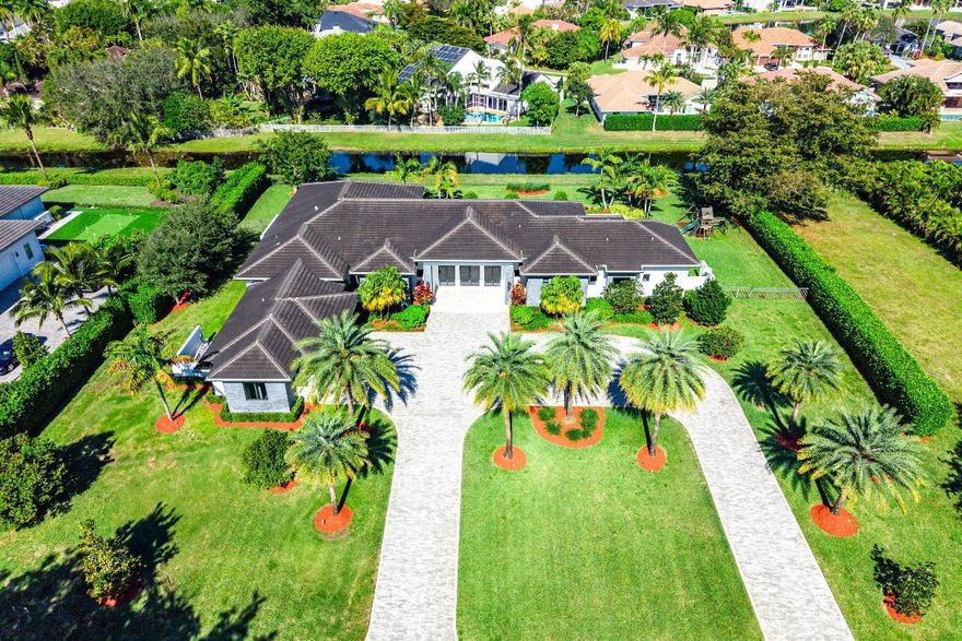 An extraordinary single-story estate offering soaring 13-foot ceilings and expansive living on a private 1-acre setting in a prestigious enclave in the heart of Boca Raton. Custom built in 2020, this residence delivers rare scale, privacy, and architectural presence, complemented by a full smart-home environment with Crestron lighting, integrated security, impact glass throughout, and a 48KW whole-house generator. Featuring 5-bedrooms, 5.5 baths, and a private office off the primary suite, the home is anchored by an expansive, beautifully appointed kitchen with top-of-the-line appliances, exceptional storage, and a massive statement island. The kitchen opens directly to a grand family room, creating a dramatic open-concept living space designed to host large gatherings. The backyard is a private resort unto itself, anchored by a sweeping lawn, resort-style pool and spa, and expansive covered outdoor living areas designed for year-round enjoyment. A fully equipped summer kitchen with Sedona gas grill creates an ideal setting for elevated outdoor entertaining, from intimate evenings to large-scale gatherings.