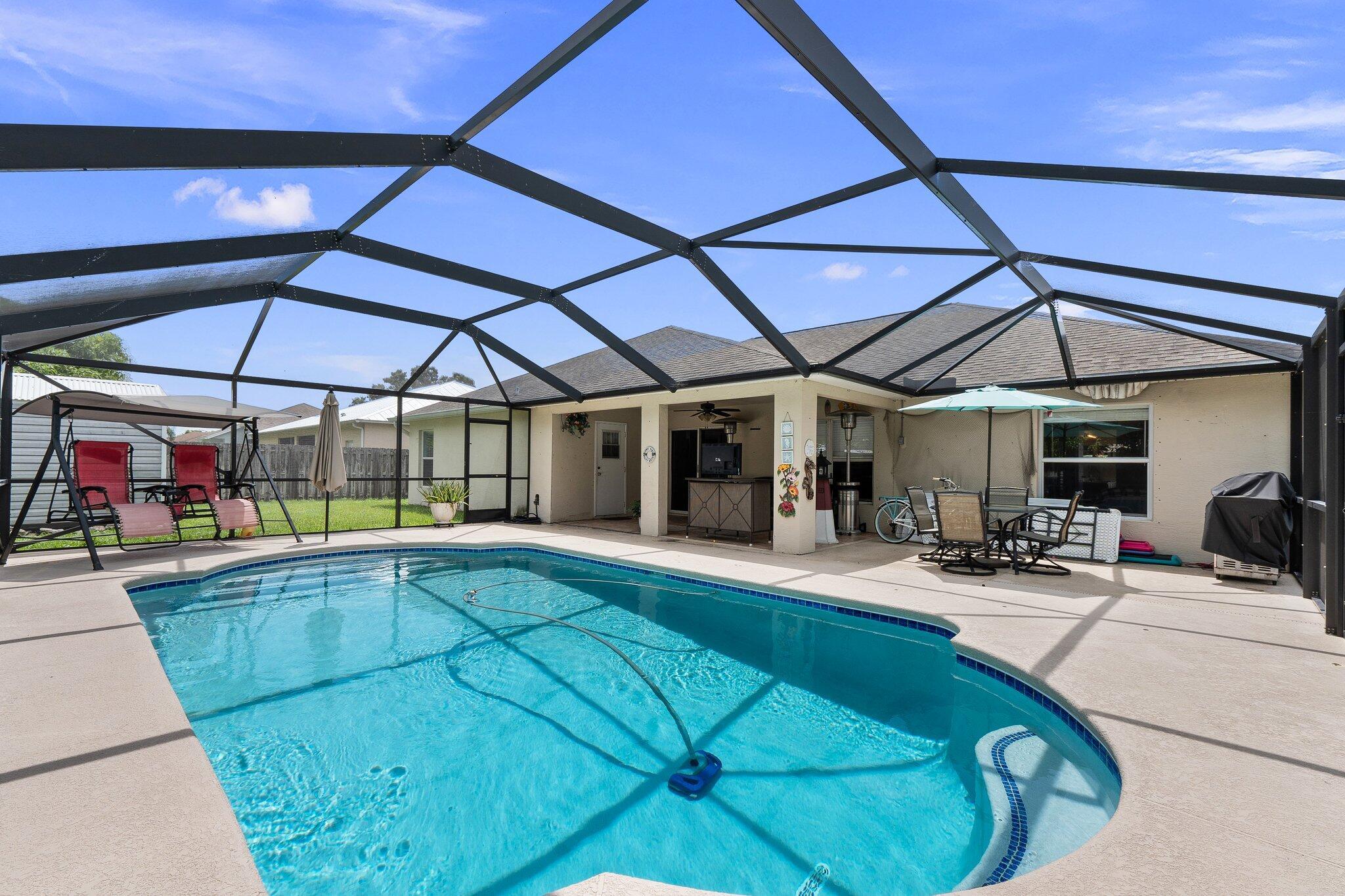 Beat the heat and make this pool home yours! Pool and enclosure installed in 2019. Fully privacy fenced and a shed. Open floor plan with large kitchen convenient to dining room and family room. Front living room is separated by half walls to make the space more functional. Vinyl flooring throughout! New roof in 2025! AC is 2020. Located centrally between Tradition and St Lucie West off of Crosstown.