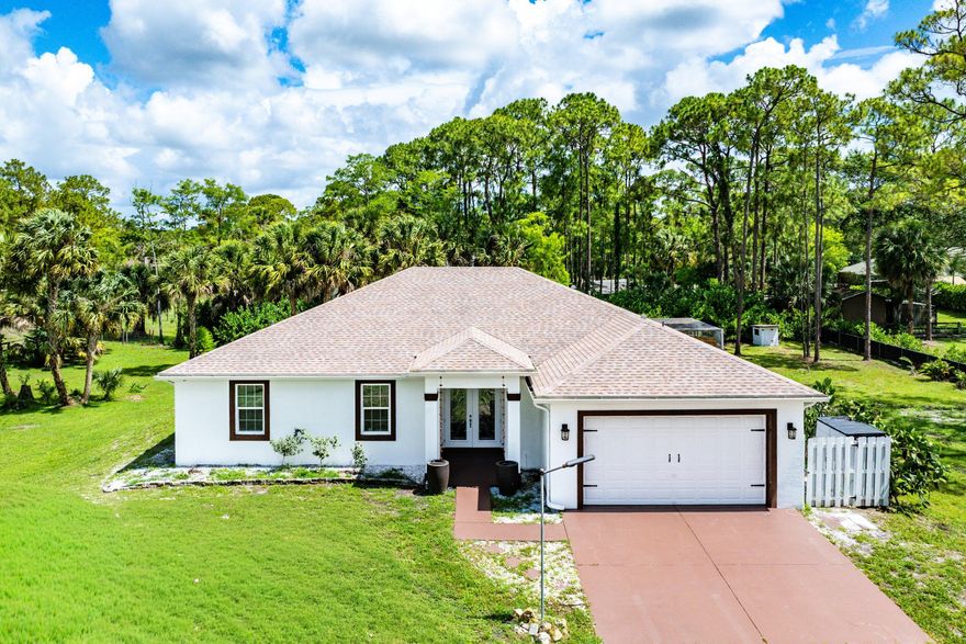 Welcome to 16215 83rd Pl N, a fully upgraded 4-bedroom, 3-bath CBS Synergy Home built in 2019 and situated on a private 1.34-acre corner lot in Loxahatchee. This property offers privacy, space, and extensive recent upgrades while remaining close to everyday conveniences. Inside, the home features an open floor plan, 9-foot vaulted ceilings, oversized windows, fresh interior paint, new light fixtures throughout, wood-look tile in the main living areas and primary suite, and marble blue tile in the guest bedrooms. The kitchen includes high-end stainless steel appliances, a double convection oven, granite countertops, white cabinetry, a new marble tile backsplash, and a breakfast bar. The guest bedrooms also feature new closet doors, while the primary bathroom was beautifully updated in 2026. Additional recent improvements include a 2025 A/C system, brand-new well pump, freshly painted front doors, and septic system cleaning completed in 2026. The home also includes hurricane impact-rated windows, two wells, and a canal that can be utilized for irrigation. The outdoor space is designed for both entertaining and everyday enjoyment, featuring a screened patio, covered lanai, expansive fenced yard, extended driveway, fruit trees, a 2025 chicken coop, and a freshly painted custom hurricane/weather-proof concrete fire pit with built-in seating. Located on a lightly traveled street less than 5 minutes from Publix, restaurants, gas, laundry, and the post office, with Westlake, schools, Wellington, PGA golf, Lion Country Safari, and the Wellington International nearby. This home offers upgraded living, usable land, and convenient access to both outdoor recreation and city amenities.