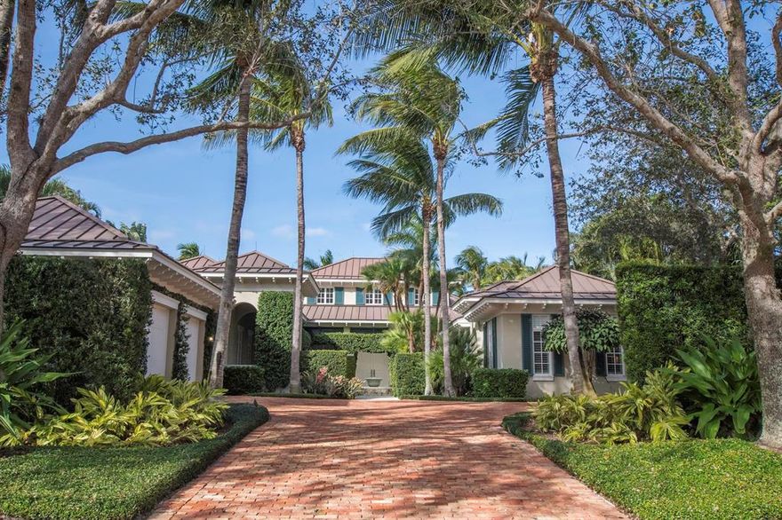 Grand Estate Home in the prestigious Loxahatchee Club with over 4,700 sq ft of living with 4 bedrooms including a private guest suite plus a home office and 4.1 luxurious baths are found in this beautiful open plan home with gorgeous lake and golf course views. Enter this home from the pavered courtyard and the peaceful sounds of a fountain and be immediately struck by the manicured landscaping. Double doors bring you inside to the two story large living room with clerestory windows, fine architectural molding and beams, a cozy fireplace and walls of glass with views to the pool and patio with the lake and golf course beyond. The adjacent kitchen is perfect for open entertaining and boasts custom white cabinetry, sparkling stainless appliances,