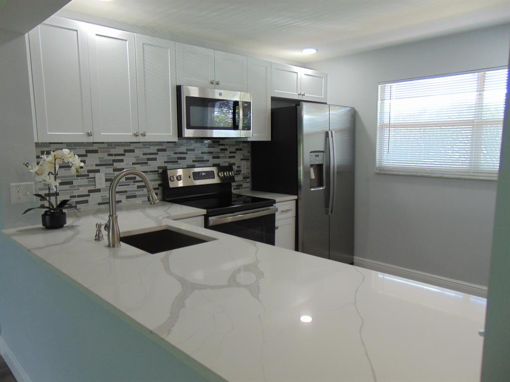 WELCOME TO THIS ATTRACTIVE FULLY REMODELED CONDO ! SHAKER KITCHEN CABINETRY, UPGRADED QUARTZ COUNTERTOP, NEW ELECTRIC PANEL, 2022 A.C. & WATER HTR, NEW WATERPROOF FLOORING MATCHING THROUGHOUT....STAINLESS KIT.APPLIANCES,NEW BATHROOMS WITH FULL BATH WITH WALK-IN SHOWER. NEW WASHER/DRYER & MORE! CONVENIENTLY LOCATED ACROSS FROM TENNIS, THE CLUBHOUSE WITH ITS POOL, MEL'S BISTRO, GYM, CLASSES, TRIPS, PAY-AS-YOU-PLAY GOLF & ANOTHER SUBDIVISION POOL SOUTH OF THE CLUBHOUSE. APPROXIMATELY 7 MILES TO THE BEACH + SHORT DRIVE TO THE TURNPIKE & SHOPPING.