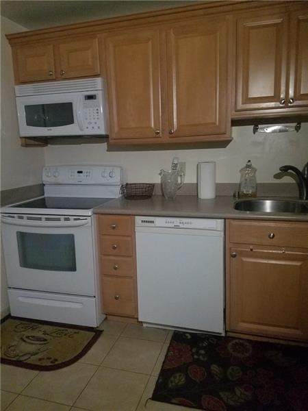 Amazing unit with tile floors overlooking the lake, featuring updated kitchen and bathrooms, in-unit laundry, and resort-style amenities at International Village including outdoor and indoor heated pools, jacuzzi, sauna, spa, gym, business center, tennis courts, barbecue area, and more.