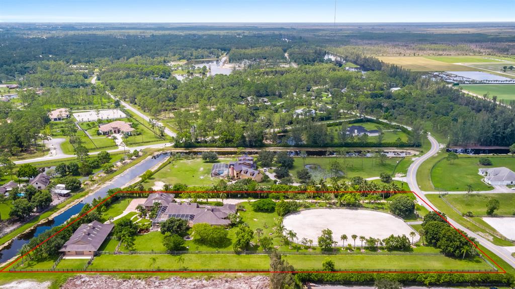 Private guard-gated equestrian community of Homeland next to Wellington. Pristine condition. This unique estate is a one-of-a-kind on 5.18-acres and over 11,000-square feet total area. Professional riding arena, new barn featuring 10-horse stalls, tack room and office. Multiple storage units and green pastures. 5+ car garages and plenty of room for additional 6+ vehicles. Interior features volume ceilings, a massive 46' X 36' recreation room, formal dining room, formal living room, breakfast and tv rooms. Very large Master Bedroom/bathroom with separate seating area and spacious 12' X 15' walk-in closet and built in fireplace. Beautiful views of the screened heated pool and custom rock waterfall. Home has been renovated and professionally decorated. READY FOR YOU TO ENJOY THE 2021 season.
