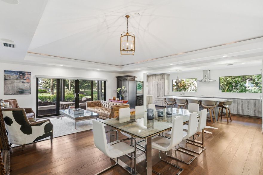 Remodeled 4BR, 4.5BA ground-floor end-unit incl. 1/1 guest suite w/ private entrance. Completely updated in 2020 with impact windows, modern kitchen/appliances, designer finishes. Split floor plan, elegant foyer, powder room. Open living/dining flows to private terrace w/ tranquil  views. Neutral palette, energy-efficient. Banyan-lined street, resort-style ambience. Move-in ready on Wellington's most prestigious street.
