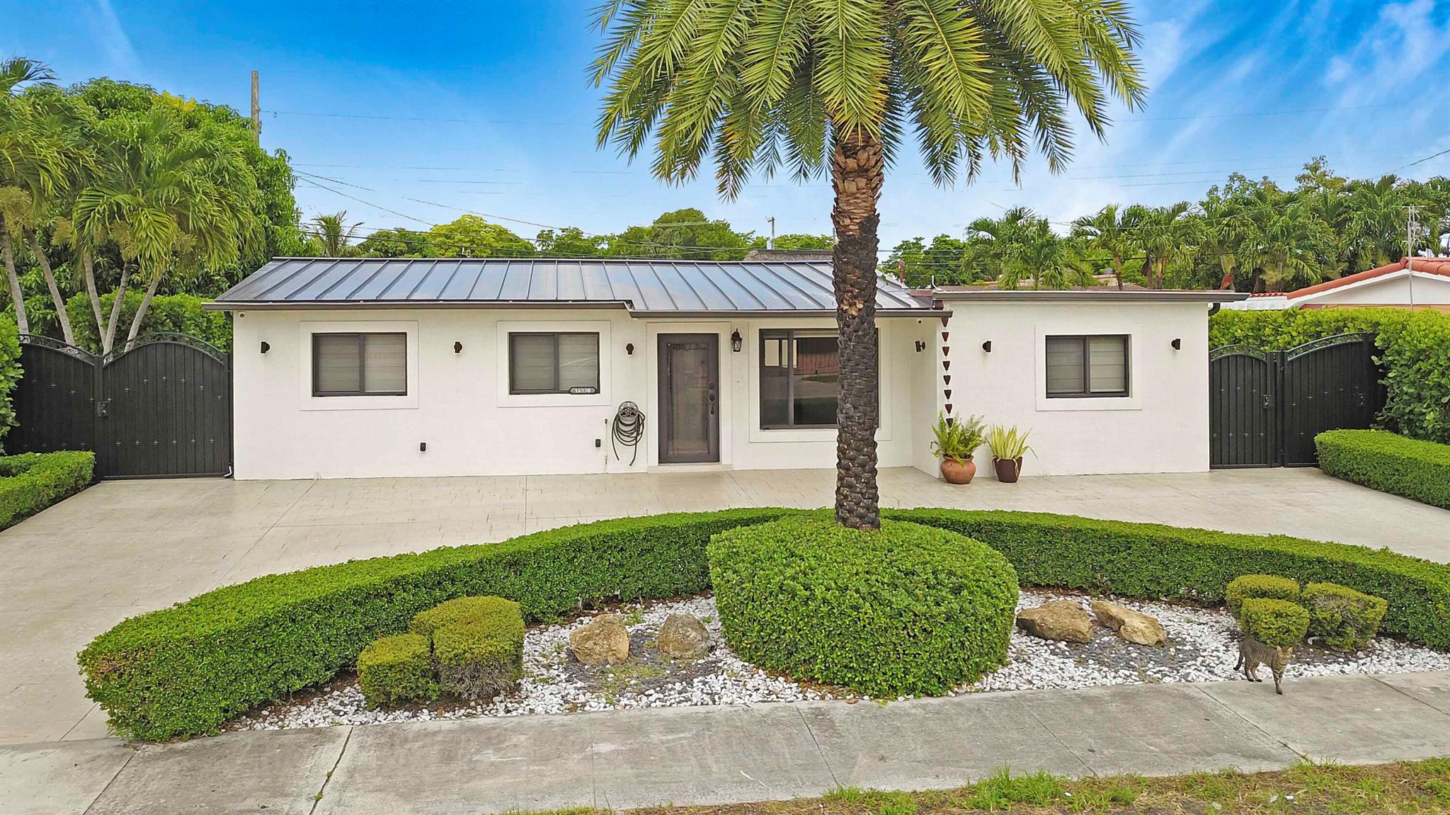 Looking for a move-in ready home with an in-law suite, a stunning kitchen, and plenty of space to entertain? This Miami Gardens gem checks every box!This extravagant 4-bedroom, 3-bathroom home--featuring an additional office/flex space--has been fully upgraded and modernized with a split floor plan and elegant porcelain tile flooring throughout.The kitchen is a showstopper, featuring sleek white high-gloss cabinets that reach the ceiling, a massive center island with a glass cooktop, striking Calacatta quartz countertops, stainless steel appliances, a built-in microwave/oven combo, and a deep stainless steel farmhouse sink.
