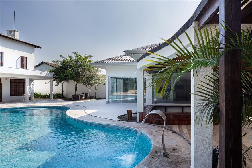 Extraordinary home in the greater Sao Paulo area (Sao Paulo, Brazil), within a gated and guarded community. Designed and built for an expatriate executive, this home was completely renovated in 2021, including a brand new roof and kidney-shaped swimming pool. The house has 5 bedroom suites, a guest apartment with separate entrance, and has luxury finishes: marble floors and wide ipê boards. The property is a private club in its own right, with an extensive outdoor living area, including a covered kitchen and party room; an official size tennis court (with markings for soccer and volleyball); and grounds that include luscious tropical vegetation with full-grown trees and ornamental plants, as well as fruit-bearing trees (avocados, mangos, other).
