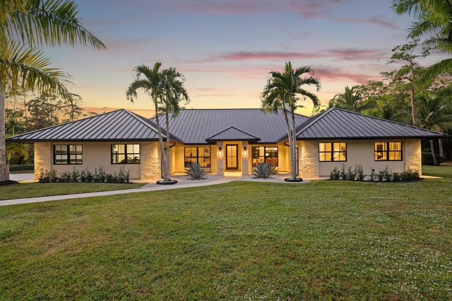 14745 Haymarket Court, a stunning 2.26-acre estate in the coveted Paddock 1 community of Wellington. Situated on a private corner lot with no immediate neighbors and no HOA, this newly completely renovated property offers unmatched tranquility and luxury. As you approach this sprawling 2.26-acre estate, elegance welcomes you at every turn, from the moment you arrive, you are greeted by an oversized driveway framed by mature royal palms, setting the tone for this grand residence. Four elegant agave plants frame the entry walkway as you enter the property. This estate's exterior is as functional as it is beautiful, with a brand-new metal roof and fresh rough cut masonry details, both completed in 2024.