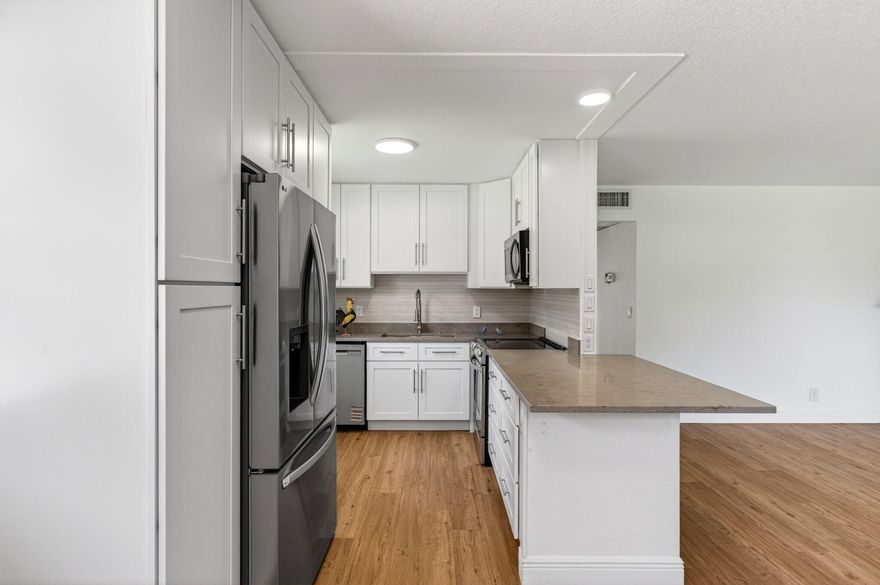 Beautifully updated 1-story villa in the desirable 55+ community of Kings Point, located just steps from the golf course. This light-filled home has been completely renovated and features all-new appliances, fresh white paint throughout, and stylish vinyl flooring. The modern chef's kitchen boasts elegant grey quartz countertops, soft-close white shaker cabinets, a light grey backsplash, and recessed lighting. Both spacious bedrooms feature sliding glass doors that bring in abundant natural light, creating a bright and airy atmosphere throughout the day.