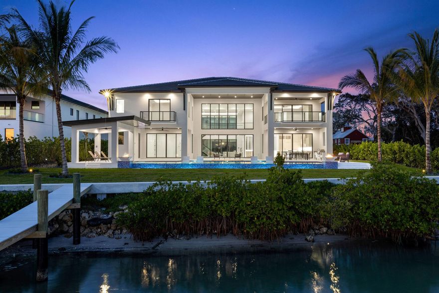 Discover this stunning waterfront masterpiece of exceptional new construction on the scenic Loxahatchee River, offering breathtaking blue water views and unparalleled luxury. Grand interiors feature 23-foot ceilings, a spectacular floating staircase, and an expansive family room, ideal for entertaining. A gourmet, chef's kitchen boasts backlit quartz countertops and seamless water views. Encompassing over 2,000 square feet, a luxurious master suite incorporates a breakfast bar, sitting room with a fireplace, two oversized closets, a spa-like bathroom, and a private balcony. Four additional bedrooms have en-suite baths, for a total of 5 bedrooms, 6 full baths, and 2 half baths. An 8-car garage with a car enthusiast's clubroom allows you to keep an eye on your prized vehicles