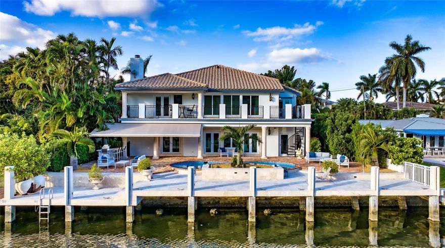Surrounded by lush landscaping, this reimagined private gated residence, with a Chicago-brick motor-court entry, offers a majestic sense of arrival. The loggia & second-floor balcony overlook 75' of water-frontage, heated pool, and new summer kitchen with a retractable awning. Inside, this 4 bedroom plus den/office European-inspired gem, with 4,689 sq ft, features rich maple and granite-slab flooring, custom molding, architectural columns & archways, hurricane-rated windows/doors, and a newer roof. Formal rooms downstairs include a dining room, breakfast room, wine cellar, office, game room, guest-bedroom, powder room, extra laundry room, and a cabana bath with storage. The master suite offers water views, a huge walk-in wardrobe, & a double vanity bath with soaking tub & walk-in shower.