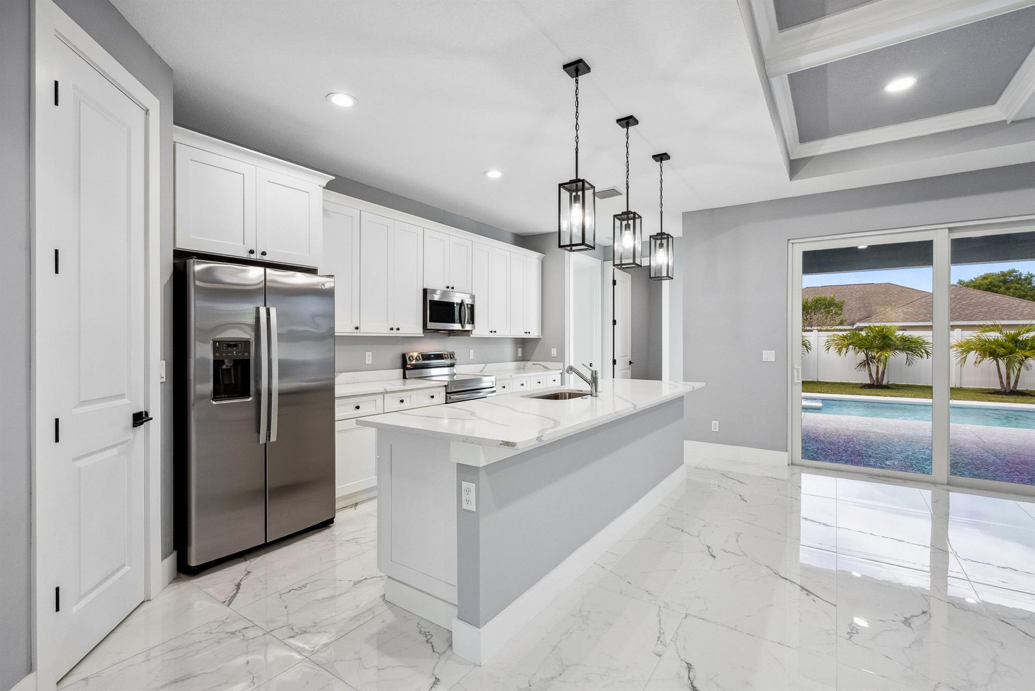 Pool home with a heated infinity spa! Fully fenced in yard for your pups! Only 1.4 miles to Tradition Square without having to pay the HOA or additional taxes to live in Tradition & only 52 minutes to the WPB Airport, making it an easy commute for a potential second home. Walking distance to Starbucks. No HOA, so bring your boat/RV! ALL IMPACT windows & doors built in 2022. Upgraded porcelain tile throughout, zero carpet. Beautiful white shaker kitchen with quartz countertops that overlooks the living room adorned with a coffer ceiling and crown molding. 8ft interior doors. The backyard is perfect to spend all summer! Two featured pergolas, an outdoor shower, extended pool cool decking and covered patio that can be easily screened for indoor/outdoor living.