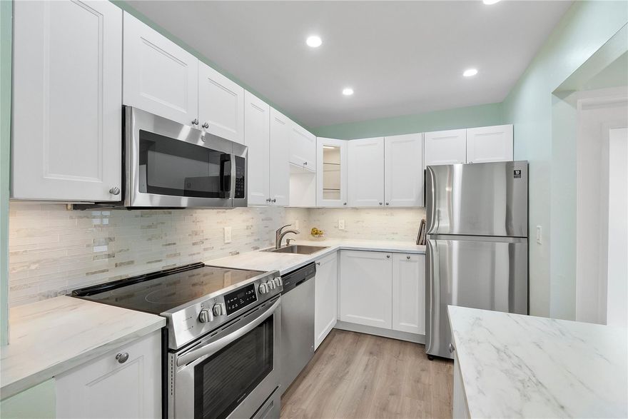 Beautifully remodeled ground floor 2 bed 2 bath condo in Lighthouse Point with assigned parking at your door. Renovated with top-quality materials, the open kitchen features stainless steel appliances and modern cabinetry. Luxury laminate floors, tile baths, and a primary bedroom with en-suite and barn doors to maximize space. Two walk-in closets and primary bath with walk-in shower and grab bars for persons with limited mobility. New impact windows and sliding door for peace of mind. Private patio with direct access to pool, clubhouse, and community areas. 55+ community with heated pool, putting green, shuffleboard, bocce, and BBQ area. One buyer must be 55+, others 18+. Perfect for seasonal or year-round living near beaches, shopping, dining, and entertainment. Low HOA and move-in ready!