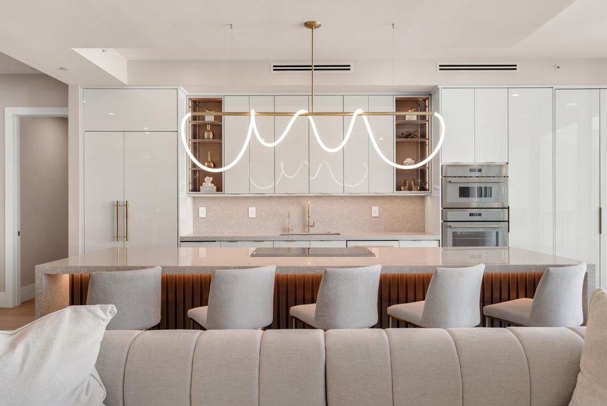 This chic 2250 square-foot penthouse features soaring 10ft ceilings, modern-statement light fixtures, simple minimalist furnishings, and a spacious balcony from every room via floor to ceiling impact-glass sliders. The great room encompasses a media lounge with a dramatic inset-ribbon fireplace, and a cocktail lounge punctuated by a bespoke 63-bottle wine wall. The centerpiece is an oversized island and open kitchen fitted with Wolf and Thermador appliances, high-gloss custom cabinetry and quartz counters. A split ensuite bedroom layout, with a primary bedroom suite including custom closets and a marble spa-inspired bathroom. The guest bedroom suite serves as an office, but is easily converted to a bedroom, Stunning powder room, large laundry/utility room. 2 garage spots.