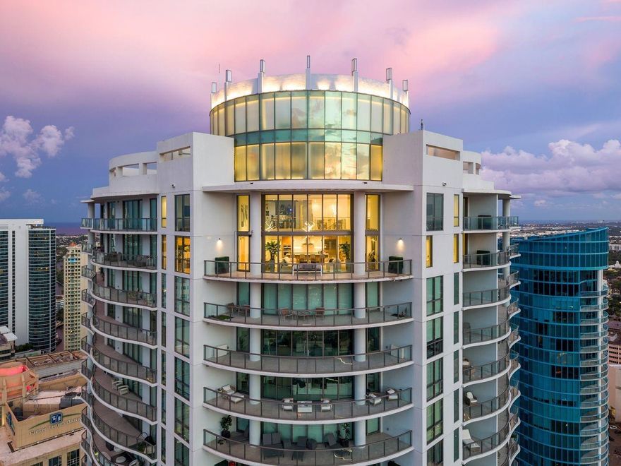 Soaring above Downtown Fort Lauderdale, 100 Las Olas is the city’s most coveted address. This one-of-a-kind, two-story penthouse—the city’s highest—offers 5,281 sq. ft. with 5 bedrooms, 6.5 baths, and 4 parking spaces. Dramatic 20–30 ft. ceilings, walls of glass frame panoramic skyline views, while a fully integrated Magnolia sound system, custom-designed televisions, professional-grade camera security, and a commercial internet network create a sophisticated smart-home environment. The open great room flows to a curved terrace for extraordinary indoor-outdoor living. With top-tier appliances, designer finishes, and world-class amenities steps from premier dining and shopping, this residence defines modern luxury.