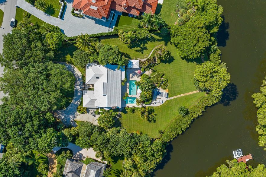 Rare 1.5 acres gem nestled in gated Seminole Landing.  Beautiful Banyan trees on water with baot access.  This 4 bedroom, 3.5 bath home features a private dock, lush tropical landscaping, pool and spa.  Intracoastal/Ocean access, 25 min to airport, 25 min to Palm Beach.  House can be shown while under contract for back up offers.