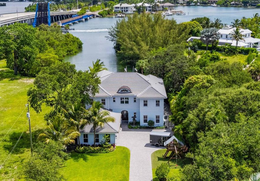 Discover this stunning Anglo Caribbean riverfront home built in 2016, located on a generous 0.62-acre lot with a private backyard. Situated in a prime location along the river and just 5 minutes from the ocean by car or boat, this spacious 7,510 sq ft residence offers an abundance of natural light and a desirable open floor plan. Featuring 5 bedrooms, 4.1 baths, two main living areas, a game room, and numerous covered patios and balconies with beautiful river views.Highlights include impact glass windows and doors, elegant wood floors throughout the first floor, a spacious master suite with a private balcony, a 10k boat lift, lush landscaping, and a stunning pool with a hot tub. This exceptional property is priced to sell!Location is everything! Jupiter is one of the most coveted