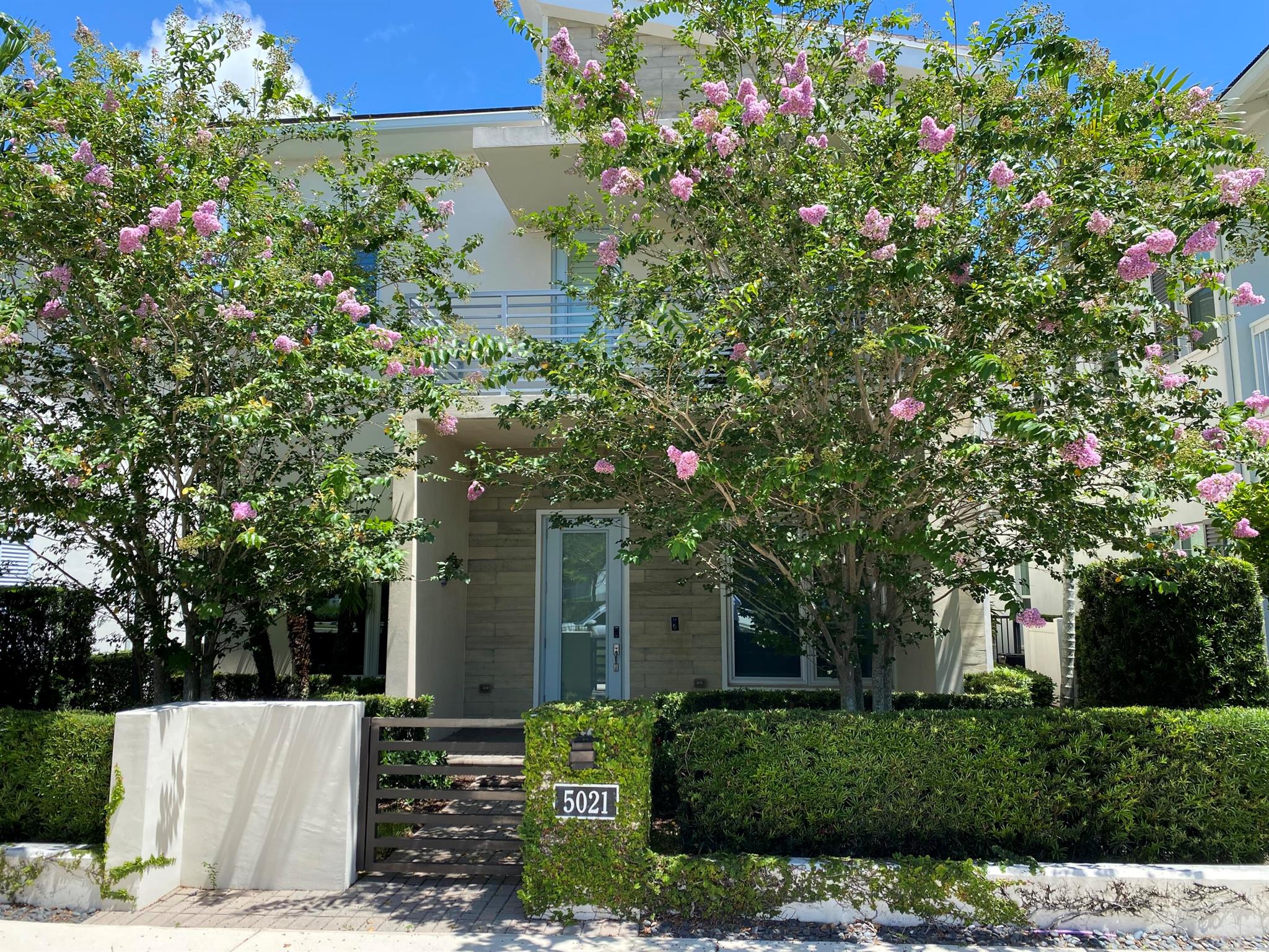 This stunning move-in ready home features porcelain floors downstairs, vinyl plank floors upstairs, custom wallpaper, designer paint, light fixtures, wood slat panels, and window treatments. The gourmet kitchen offers granite countertops, high-end appliances, and a built-in refrigerator. A stylish lounge with wet bar has replaced the downstairs office--perfect for entertaining.Upstairs, the owner's suite includes 2 walk-in closets, a spa-style bathroom and a private balcony. There's also 3 additional bedrooms, plus a home gym and a 5th bedroom, currently used as an office.Enjoy a private outdoor oasis with pool, hot tub, and summer kitchen. A 3-car garage offers ample storage, while security cameras and keypads provide peace of mind.Close to the I-95 and the Turnpike, 20 mins to PBI.
