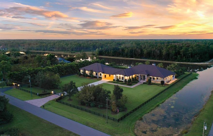 Beautiful lakefront home in the gated equestrian community of Homeland! 4 years new the home offers an open concept floorplan for ease of living with resort-like outdoor areas with stunning sunset views over the lake. The home boasts tile floors throughout, ctr-island kitchen w/ quartzite counters, gas cooking, double refrigerators, 2 fireplaces, impact windows & doors, 14' ceilings & a luxurious master-suite.  You'll love entertaining poolside with the water & fire features, summer kitchen, firepit, tiki bar & dock. The main house  is 4,845sqft/ac & mancave is 1,220sqft/ac. Also under air are the firing range & dog kennels. The RV/hangar garage & workshop with 14'x24' hangar door offer the ability to house up to 17 cars on property. A must see for the active family w/ all the toys!