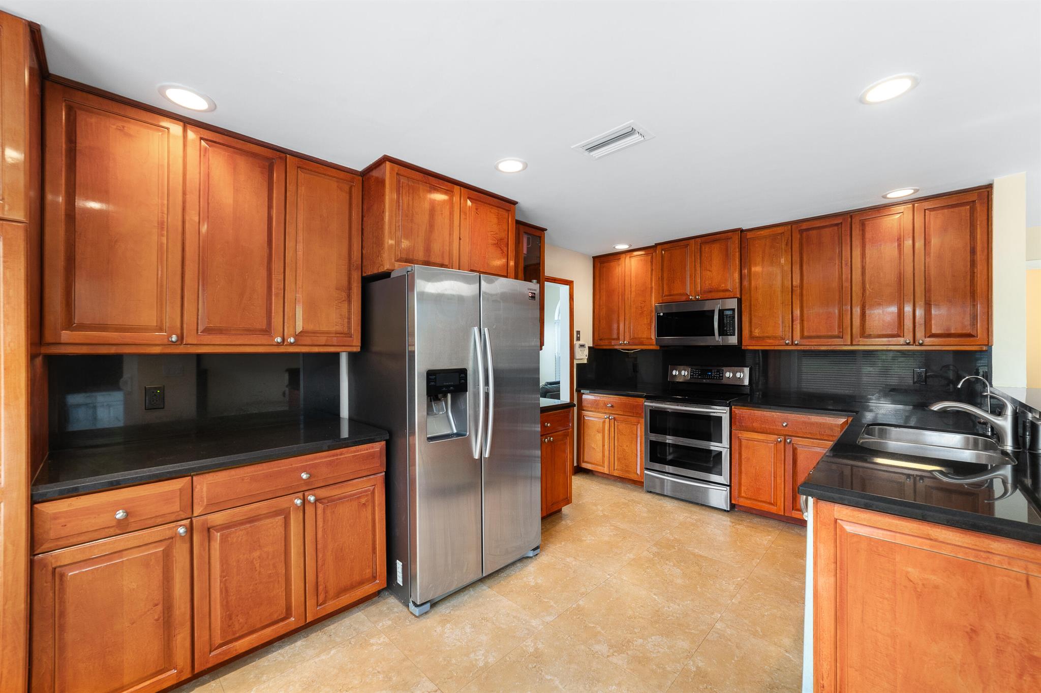 Tucked away in Coral Lake Estates, this charming 3-bedroom, 2.5 bath home offers 2,036 sq. ft. of inviting living space, highlighted by tranquil canal views and a backyard that feels like your own private nature retreat. Soaring ceilings, impact windows and doors, and abundant natural light from generous windows create a bright and airy atmosphere throughout. Downstairs, tile flooring provides durability and style, while warm wood flooring upstairs adds a cozy touch. The thoughtfully designed kitchen opens to a spacious covered patio complete with a summer kitchen, ideal for relaxing or entertaining guests. One of the home's standout features is the primary suite's closets, yes, plural, including one that's the size of a bedroom.