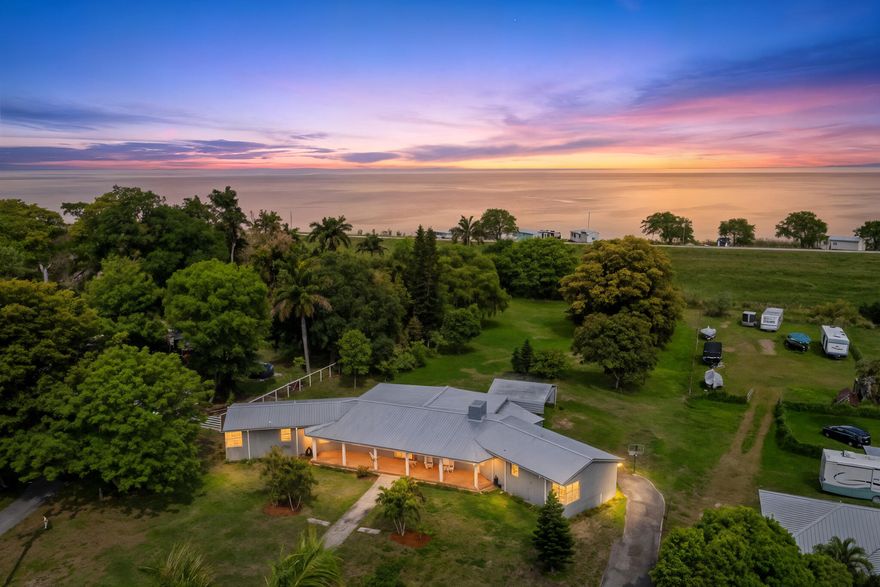 Enjoy stunning sunrises overlooking acres of cornfields from the covered Mexican tile porch, with unforgettable sunsets to close the day. Cross over your very own bridge and see Lake Okeechobee which covers 730 sq miles. This renovated single-story ranch home features mango, avocado, dragon fruit, soursop, lemon, and guava trees on the property. Horses welcome. CBS construction completely renovated, including 18" porcelain tile floors, fireplace, kitchen/appliances, master suite & bath, Three 2.5 ton AC units (2017), Two water heaters (2017), roof (2024). Impact fiberglass double doors in the front & 2 metal doors in rear. Attached shed for ride mower, storage space, tools, bikes etc.,, 12-foot Carolina double carport. A must see that won't last long.