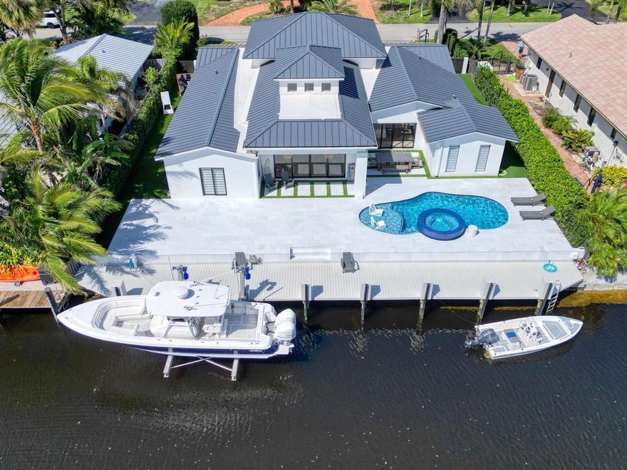 Discover the ultimate in luxury living with this stunning, brand-new 5-bedroom, 3.5-bath contemporary single-story home, perfectly positioned on a prime deep-water canal. Spanning 4,184 total sq. ft. on a 10,350 sq. ft. lot, this exclusive residence offers over 90 feet of deep-water frontage, including a 17,000-pound elevator boat lift, with no fixed bridges, (10) 4' Jet Filters along the 90' Sea Wall, just minutes from the Intracoastal and two inlets. Eastern exposure, paired with a 360-degree cupola, bathes the home in natural light, highlighting its modern design and premium materials.The custom architectural masterpiece features a split floor plan that seamlessly merges indoor and outdoor spaces, ideal for coastal living. Soaring ceilings, a grand front