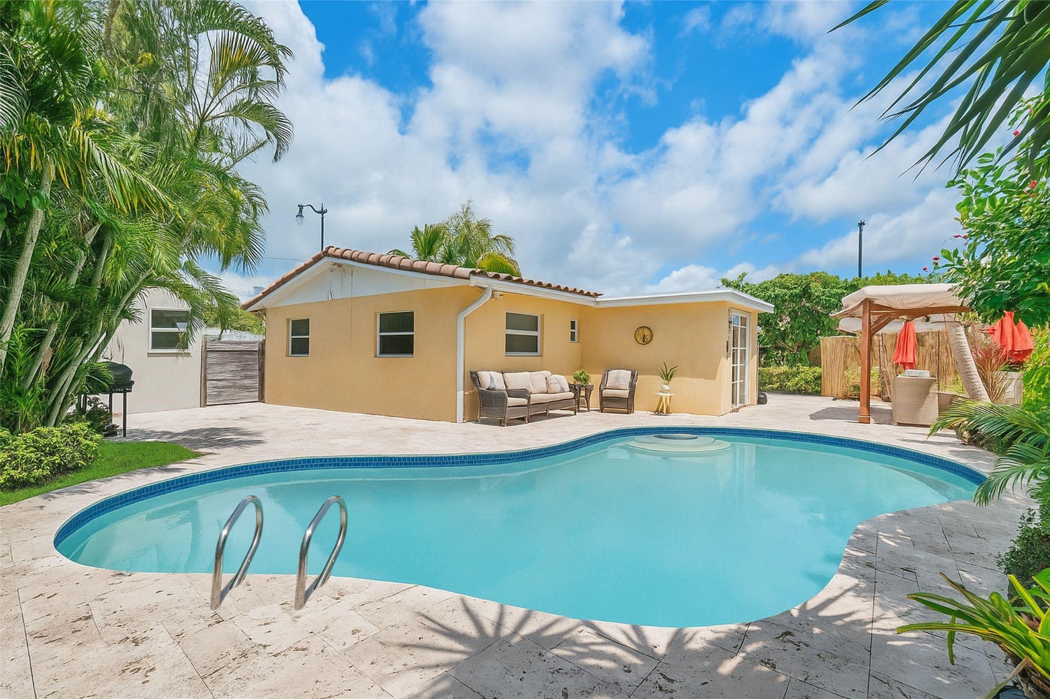 Welcome to your private tropical oasis on a spacious corner lot in the heart of Pompano Beach! Beautifully maintained 3 BR/2 BA home offers impact windows, 1-car carport + ext. drive for 3 add’l cars. Open layout w/ tile in living areas, wood in BRs, updated open kitchen w/ granite & island, remodeled baths, laundry rm + storage.
Fenced backyard retreat featuring a freeform pool with travertine patio decking, a stand-alone storage shed, a Gazebo & lush landscaping. A licensed nursery enhances the tropical setting, making this property truly unique. Major updates include: cast iron pipes relined, roof (2017), and pool resurfaced within the last 5 years. With indoor/outdoor living spaces and a resort-style atmosphere, this home is perfect for entertaining or relaxing in total privacy.