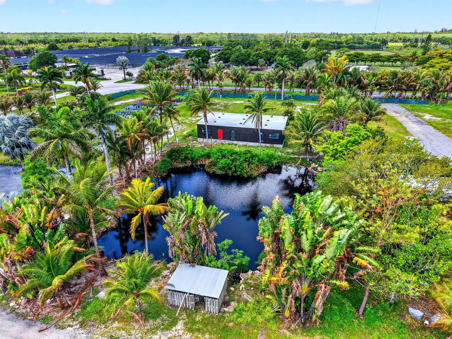 Presenting a rare and versatile commercial compound set on sprawling, picturesque 9.54  acreage on a corner lot surrounded by lush tropical landscaping and mature palm trees. This unique property offers an ideal blend of functionality, privacy, and future potential, perfect for business owners, investors, or those seeking a flexible live/work environment. At the heart of the property is a substantial industrial-style warehouse featuring multiple oversized roll-up bay doors for seamless access and efficient workflow. The structure boasts high ceilings, durable concrete flooring, and a wide-open layout that accommodates a variety of uses, from storage and distribution to light manufacturing or contractor operations. Inside, the warehouse is already outfitted with shelving, workspace areas, and equipment zones, allowing for immediate use while still offering room for customization.  Attached and adjacent interior spaces are partially built out, showcasing framed walls, exposed beams, and installed drywall, providing a strong foundation for offices, studios, showrooms, or specialized production areas. These interiors offer a blank canvas ready to be finished to your exact specifications, making it easy to tailor the property to your operational needs or creative vision.  In addition to the main warehouse, the property includes a separate standalone building that can serve as administrative offices, client-facing space, or additional workspace. This structure enhances the property's functionality by allowing for separation between operations and business management, or even the potential for multiple tenants or uses.  The grounds themselves are equally impressive. The expansive acreage is dotted with mature trees, open green spaces, and cultivated areas that could be utilized for agriculture, landscaping operations, or outdoor storage. The serene, park-like setting offers both privacy and inspiration, while still maintaining convenient access to surrounding areas. Wide driveways and open access points make maneuvering large vehicles, equipment, or deliveries simple and efficient.  Whether you're looking to establish a thriving business hub, expand an existing operation, or invest in a property with strong upside potential, this estate delivers unmatched flexibility. Its combination of industrial infrastructure, build-out potential, and natural surroundings creates a truly one-of-a-kind opportunity.