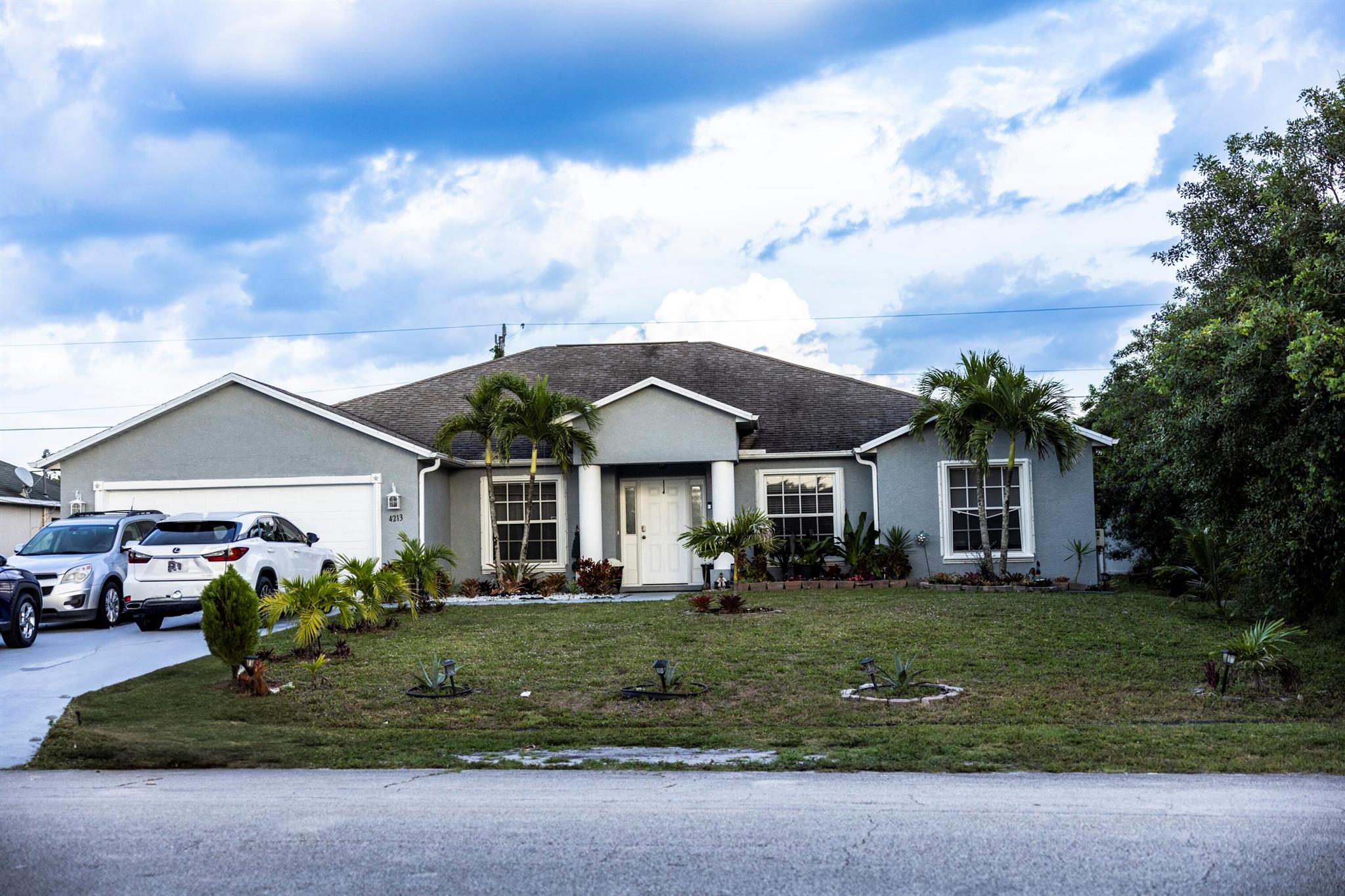 This beautiful high vaulted ceiling home is located in port St. Lucie .25 Acre has 4-bedrooms, 3-baths, 2- car garage and a nice screened patio where you can enjoy watching movies with your family. A/C 2020, Hot water heater 2024,Luxury tile and wood floor, only one bedroom has carpet, the master bedroom looks amazingly beautiful. The front of the house is well maintained with a beautiful flower garden. and some fruit trees in the back with a sprinkling system.(plants in pots, and chandelier in the master bedroom do not convey.