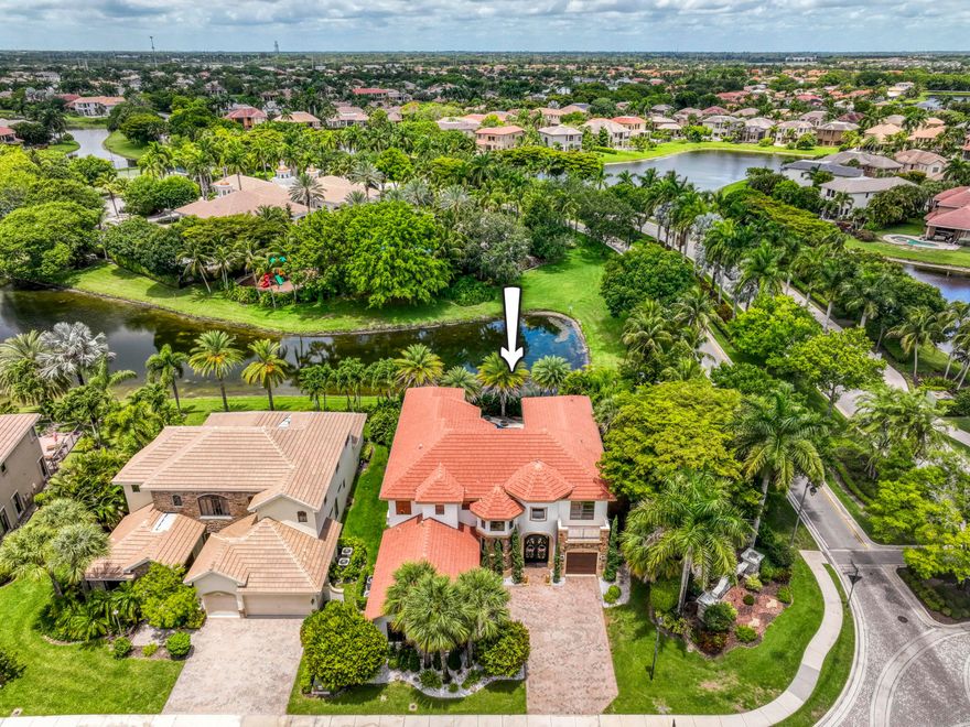 A private backyard paradise with a custom Van Kirk pool, tiki huts, fireplace features, and tranquil lake views makes this stately Versailles home truly unforgettable. Offering 5 bedrooms, 6 bathrooms, a den/theater room, and over 4,100 sq ft under air, this beautifully maintained residence blends luxury, comfort, and entertaining space in one of Wellington's most desirable communities. Inside, Turkish marble flooring spans the entire first floor, while Krono Swiss wood flooring enhances the stairs, upstairs hallway, and spacious primary suite. The open living spaces are filled with natural light and overlook the resort-style pool and waterfront views. The kitchen features Patagonia White Fusion granite countertops and backsplash, high-end Samsung appliances, a center island, and direct views of the outdoor oasis. The family room is spacious and inviting with bay windows, recessed lighting, and upgraded 6-inch baseboards, while the den has been transformed into a custom theater room with specialty carpeting and drapery. The expansive primary suite includes a private balcony overlooking the lake and pool, a spa-style bath with jacuzzi tub, and a custom en-suite layout.  Outside, enjoy a spectacular custom pool built by Van Kirk & Sons complete with gas fire bowls, two tiki huts, lush landscaping redone in 2020, and incredible privacy. Additional highlights include a Generac whole-house generator, impact front door, epoxy garage flooring, updated garage motors, three A/C zones, and custom window treatments throughout. Located in the highly sought-after Versailles community with low HOA fees, residents enjoy a resort-style clubhouse, pool, fitness center, playgrounds, parks, and top-rated Wellington schools.