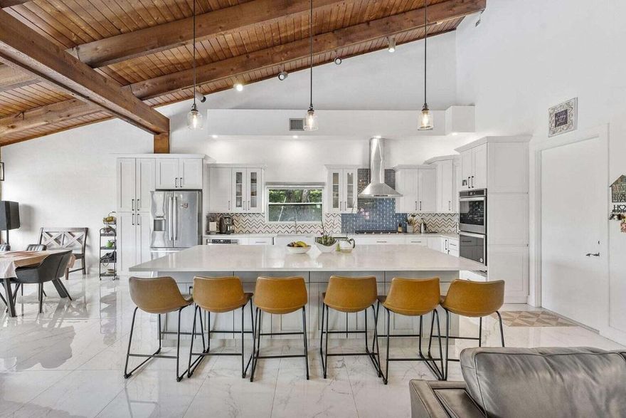 Modern yet inviting, this reimagined residence offers 2,897 sqft of living space (3,972 total) on a private cul-de-sac of only 20 homes—peaceful, secure, and ideally located. Thoughtfully updated with soaring wood-beam cathedral ceilings, oversized porcelain tile floors, and floor-to-ceiling windows that fill the home with natural light. The open layout flows to a resort-style travertine pool deck overlooking the golf course—perfect for entertaining or relaxing. The chef's kitchen features a quartz island, propane cooktop, double oven, wine fridge, and farmhouse sink. 5 bedrooms plus loft, 3 full baths, and 3-car garage. No HOA! Enjoy flexibility within a well-kept neighborhood close to top schools, Costco, FAU, Lynn Univ., downtown Boca & Delray, beaches, and major highways.