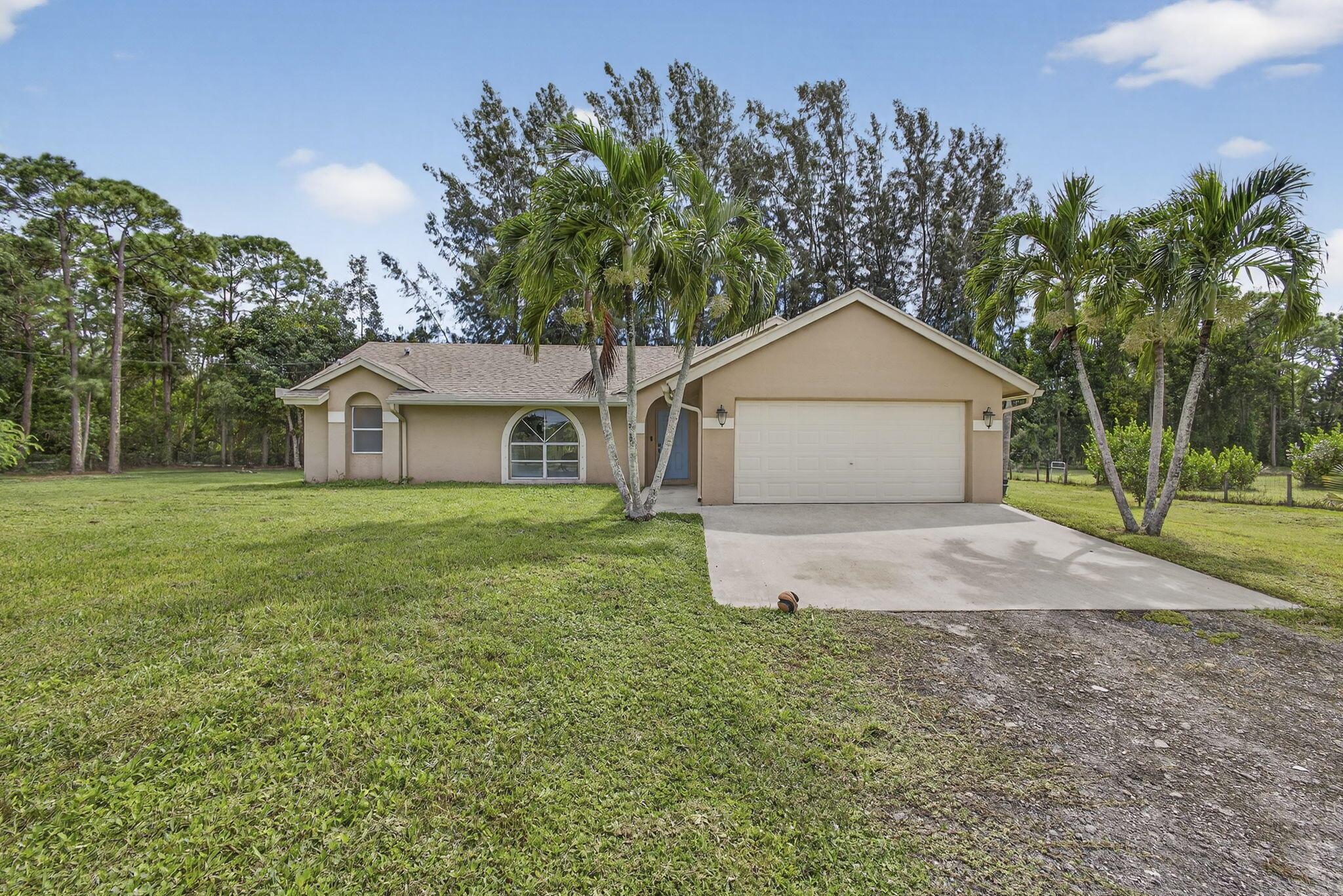 Experience country living just minutes from the new City of Westlake! This 3-bedroom, 2-bath CBS home with a 2-car garage sits on 1.29 fully fenced acres at the end of a quiet paved street. The split floor plan features two living areas with vaulted ceilings, creating an open, airy feel, and vinyl flooring in the living areas. The kitchen boasts solid wood cabinets, granite countertops, and stainless steel appliances. French doors open to a spacious backyard and patio, ideal for entertaining. With no HOA, enjoy the freedom to bring horses, boats, RVs, or trailers. The oversized lot offers room for a pool, workshop, or guest house providing endless possibilities for Florida country living.