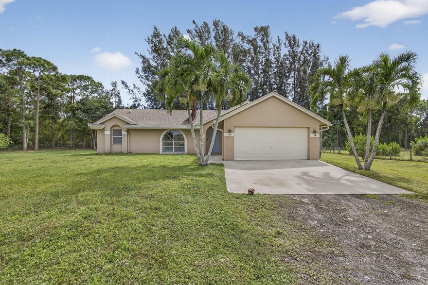 Experience country living just minutes from the new City of Westlake! This 3-bedroom, 2-bath CBS home with a 2-car garage sits on 1.29 fully fenced acres at the end of a quiet paved street. The split floor plan features two living areas with vaulted ceilings, creating an open, airy feel, and vinyl flooring in the living areas. The kitchen boasts solid wood cabinets, granite countertops, and stainless steel appliances. French doors open to a spacious backyard and patio, ideal for entertaining. With no HOA, enjoy the freedom to bring horses, boats, RVs, or trailers. The oversized lot offers room for a pool, workshop, or guest house providing endless possibilities for Florida country living.