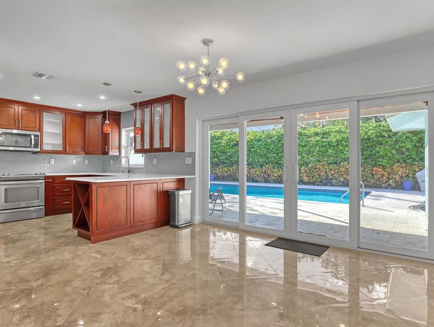 Upgrades include a brand-new HVAC system, tankless water heater, upgraded electrical panel with generator transfer switch, PGT impact windows, and a recently resurfaced 35-foot saltwater pool with a new variable-speed pump. The home features an ideal split floor plan, 24-inch porcelain tile flooring, recessed lighting, and a two-car garage with newly finished Ox Floors (lifetime warranty) and built-in shelving. The kitchen offers wood cabinetry, quartz countertops, stainless steel appliances, a wine cabinet, a stylish backsplash, and pendant-lit breakfast bar seating. Outdoor highlights includ