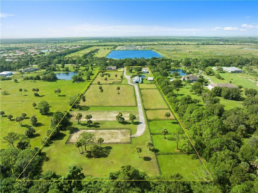 8.63-acre equestrian property in Vero Beach featuring a pond, mature oaks, fully fenced grounds, three barns with over 9,000 sq ft of covered space, 16 stalls, 2 feed and tack rooms, and bathroom facilities, a dressage arena, schooling arena, and multiple turn-out paddocks. The 3-bedroom, 2-bath CBS ranch home offers a split layout with walk-in closets, open kitchen with stainless appliances, and vinyl flooring throughout. The house has a large extra space that can be converted into a mother in law or helper's apartment. Paver patio and open porch. The 30x15 heated pool rounds out the outdoor space. Newer roof, AC, and water heater. County water and paved road access.