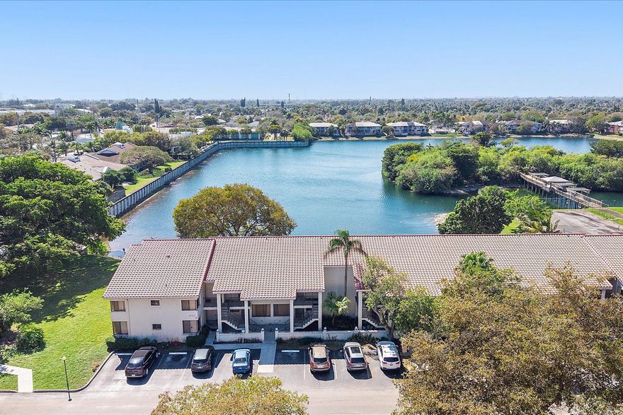 Enjoy peaceful lake views from this inviting 2-bedroom, 2-bath condo in Mira Lago, offering 1,075 square feet of well-planned living space. This light-filled residence features an open layout with volume ceilings that create an airy feel throughout. The primary suite includes a walk-in closet and an updated bath with a tiled shower and floor. Wood flooring enhances the main living areas, and the kitchen includes a brand-new stove. Relax on the screened patio overlooking the water. Located in a gated community with a pool and convenient access to shopping, dining, and well positioned near major routes.