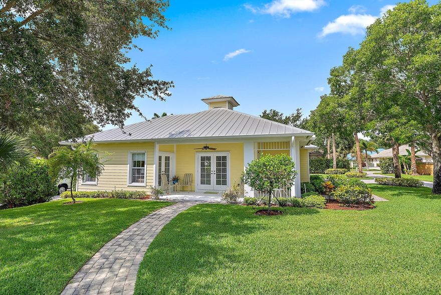 *Available Annually or Seasonally*  Charming Cottage in Jupiter - Tucked away on a serene and meticulously maintained private estate in Jupiter, this charming 2-bedroom, 2-bath cottage offers a unique blend of privacy, comfort, and coastal style. With its cheerful yellow exterior, metal roof, and welcoming front porch, the home captures the essence of classic Florida living. Inside, the open floor plan is bathed in natural light and features coastal-inspired furnishings, tile flooring throughout, and a spacious kitchen with breakfast bar seating. The living area flows seamlessly to a private patio through French doors, perfect for enjoying the surrounding greenery. Both bedrooms are comfortably appointed, and the primary suite offers generous closet space and garden views.  Enjoy the ease of an in-home laundry room, a private garage, and access to beautifully landscaped grounds that provide a tranquil setting, just minutes from Jupiter's finest beaches, golf clubs, and waterfront dining. Offered fully furnished. Available for seasonal or annual rental. Ideal for those seeking a peaceful getaway or extended stay on a premier estate property in one of South Florida's most desirable locales.