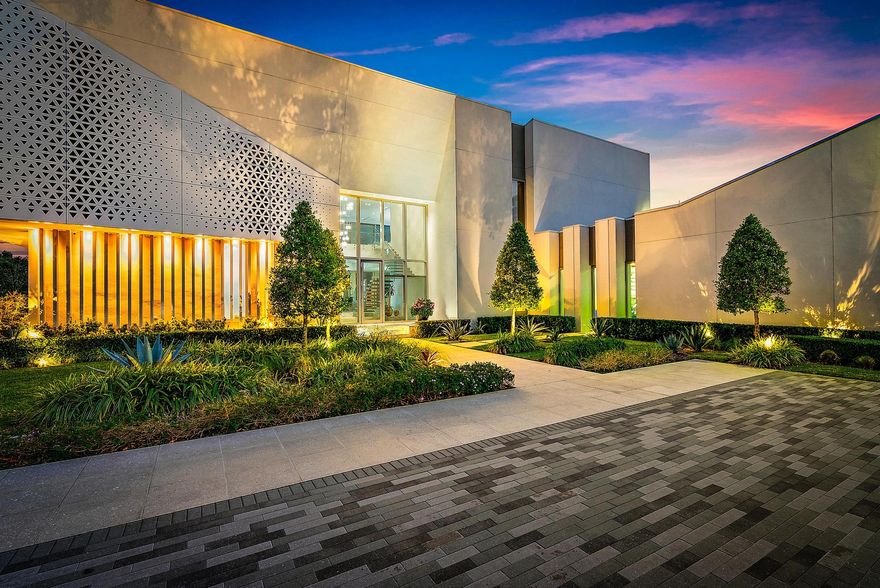 Welcome to a truly distinctive modern estate in Palm Beach Gardens—an ultra-luxury architectural showpiece that seamlessly blends innovation, refined design, and tranquil surroundings. Encompassing 11,144 square feet, this custom-built residence offers five bedrooms, eight full baths, and two half baths, all set amidst serene, Japanese-inspired landscaping. Constructed under the owner's direct oversight, the home reflects exceptional craftsmanship and uncompromising attention to detail.  A dramatic two-story vestibule makes a striking first impression, featuring a glass-suspended staircase, a glass-enclosed commercial elevator with a custom artistic mural finish, and a floor-to-ceiling glass façade that captures picturesque garden views.  The grand living room is filled with natural light, highlighted by a soaring 25-foot ceiling and a sleek ribbon fireplace set against blue lacquered panels that discreetly conceal media. Expansive 10-foot sliding glass doors open to a private outdoor retreat, complete with lush gardens and a sunlit 75-foot lap pool with spa.  The elegant dining room offers a refined setting with a tray ceiling and peaceful pool views, while the family room flows effortlessly into the chef's kitchen. Outfitted with professional-grade appliances, an oversized butler's pantry, and custom cabinetry, the kitchen also features a large work island and a floating breakfast bar.  The first-floor primary suite serves as a private sanctuary, with walls of glass opening to the pool and gardens. This luxurious retreat includes dual custom walk-in closets and two spa-inspired bathrooms finished in full marble slabs, each equipped with steam showers and Toto bidet toilets.  Designed for both grand entertaining and everyday comfort, the home features an indoor-outdoor loggia with a summer kitchen, a fully equipped gym, a library, two guest suites, and a four-car garage on the main level. Upstairs, a nine-seat custom theater, two additional bedroom suites, and a lounge with kitchenette provide an ideal setup for guests.  Additional highlights include 10-foot ceilings and doors throughout, stainless steel panelized framing, impact-rated insulated glass windows, automated shades, imported rain showers, flush Italian doors, a Savant smart home system, whole-house generator with propane tanks, eight-zone air conditioning, and instant hot water systems.