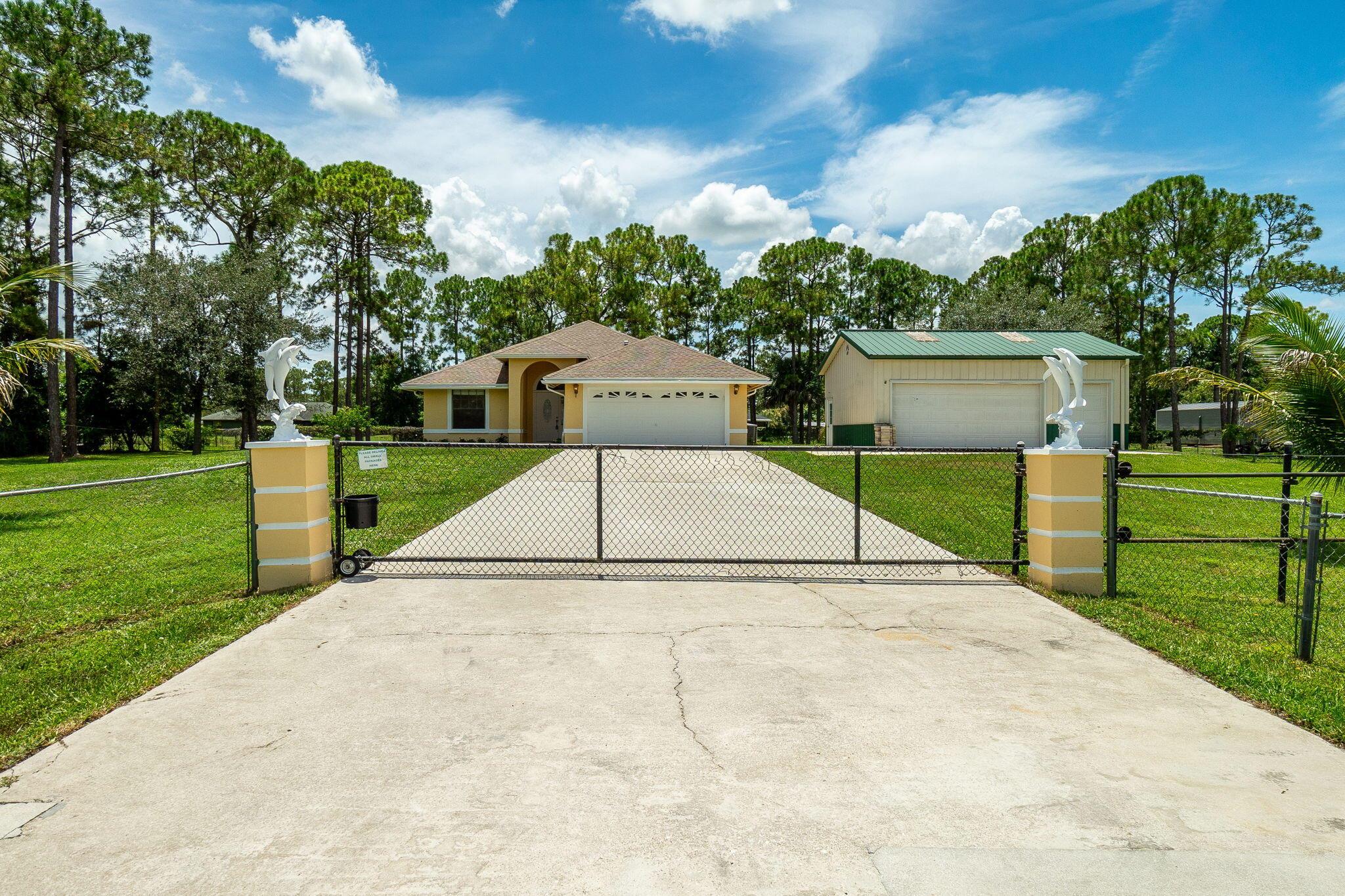 Welcome to this rare Loxahatchee gem--This solid CBS Constructed Home features 2016 Roof & A/C, 2025-Hot Water Heater, Vaulted Ceilings, 3-bedrooms, 2-full baths, Large Kitchen w/whitewashed cabinets, beautiful bay window looking out to the fabulous fully fenced-in 1.28 acres w/ Palm Trees, Mango and Papaya Trees. Large Screened in Patio w/Fiberglass Pool and Cedar tongue-n-groove ceiling in covered patio. The main Bath has a separate Lg. Soaking Tub & Shower, Two Walk-in-closets. Interior Laundry Room. The property is fully fenced in with Expansive Concrete Driveway and Gate. PLUS ++ There is a HUGE 30' x 24'= 720sqft Detached Metal Building Garage w/Power & Water!!! There is plenty of room for Business/Workshop and storage all your toys!!! A Must See!!!