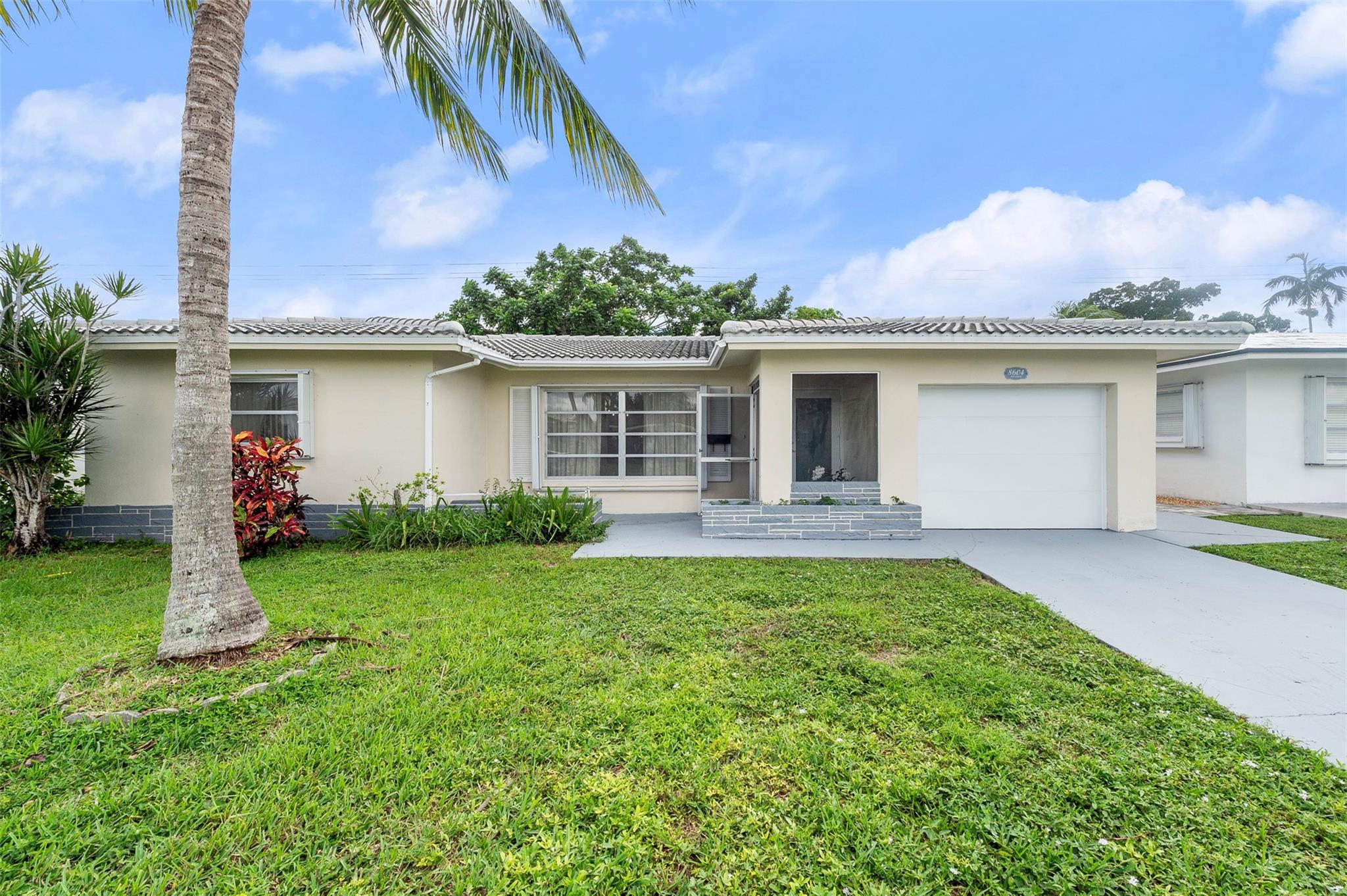 Welcome to your tropical oasis! This charming 2-bedroom, 2-bath home offers comfort, space, and peace of mind with a new impact door, a newer roof (2023), and a 2023 water heater and 2023 A/C. The new garage doors and accordion shutters add extra security and value. Inside, you’ll find oversized bedrooms and a spacious enclosed Florida room—perfect as a sunroom, office, or easily converted third bedroom. Enjoy indoor-outdoor living in your large backyard surrounded by lush tropical fruit trees, including mango, soursop, ackee, and June plum—a true paradise for nature lovers. Don’t miss this beautifully maintained home with modern updates and endless potential!