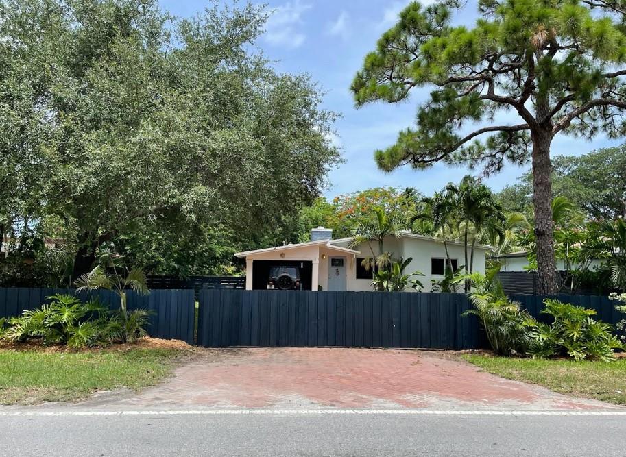 This stylish mid-century home has soaring ceilings throughout, a fully fenced gated triple lot. It's the perfect home for entertaining & relaxing! The home welcomes with a gated brick paver driveway & the coveted carport; there will always be a spot to park your car out of the hot Florida sun. The carport also has a laundry & storage area. Inside the home the living room shows off w/a classic mid-century white brick fireplace (decorative use only) a dining area & a TV room all connected for great flow. The kitchen is fresh & inviting w/Sub Zero fridge, a long bamboo island w/storage & seating for 4. The kitchen connects seamlessly w/the garden thru a back door onto the patio. Two bedrooms & a sun-filled bathroom round out this classic home. Have a dog? The yard will be your private park.